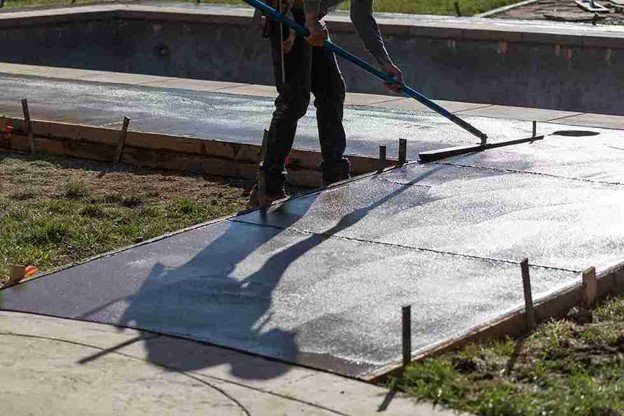 Concrete driveway installation with a worker smoothing freshly poured surface using a finishing tool in North Ridgeville, OH