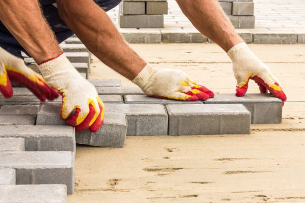 Contractor installing concrete pavers for patio construction on a leveled sand base in North Ridgeville, OH