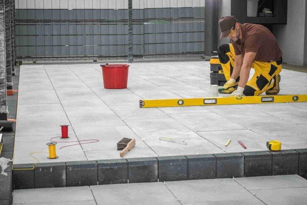 Contractor using a level tool to align large concrete patio slabs during installation in North Ridgeville, OH