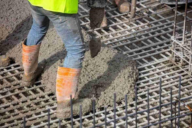Worker pouring fresh concrete over steel rebar grid for structural slab construction in North Ridgeville, OH